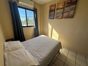 Une chambre à coucher avec un lit, une fenêtre avec des rideaux et trois tableaux accrochés au mur.