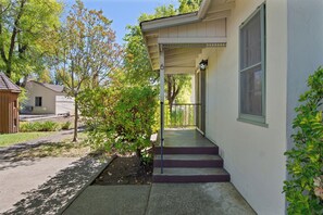 A residential house with a covered porch, a small garden, and a clear sky. - Hideaway Cottages  (Calistoga)