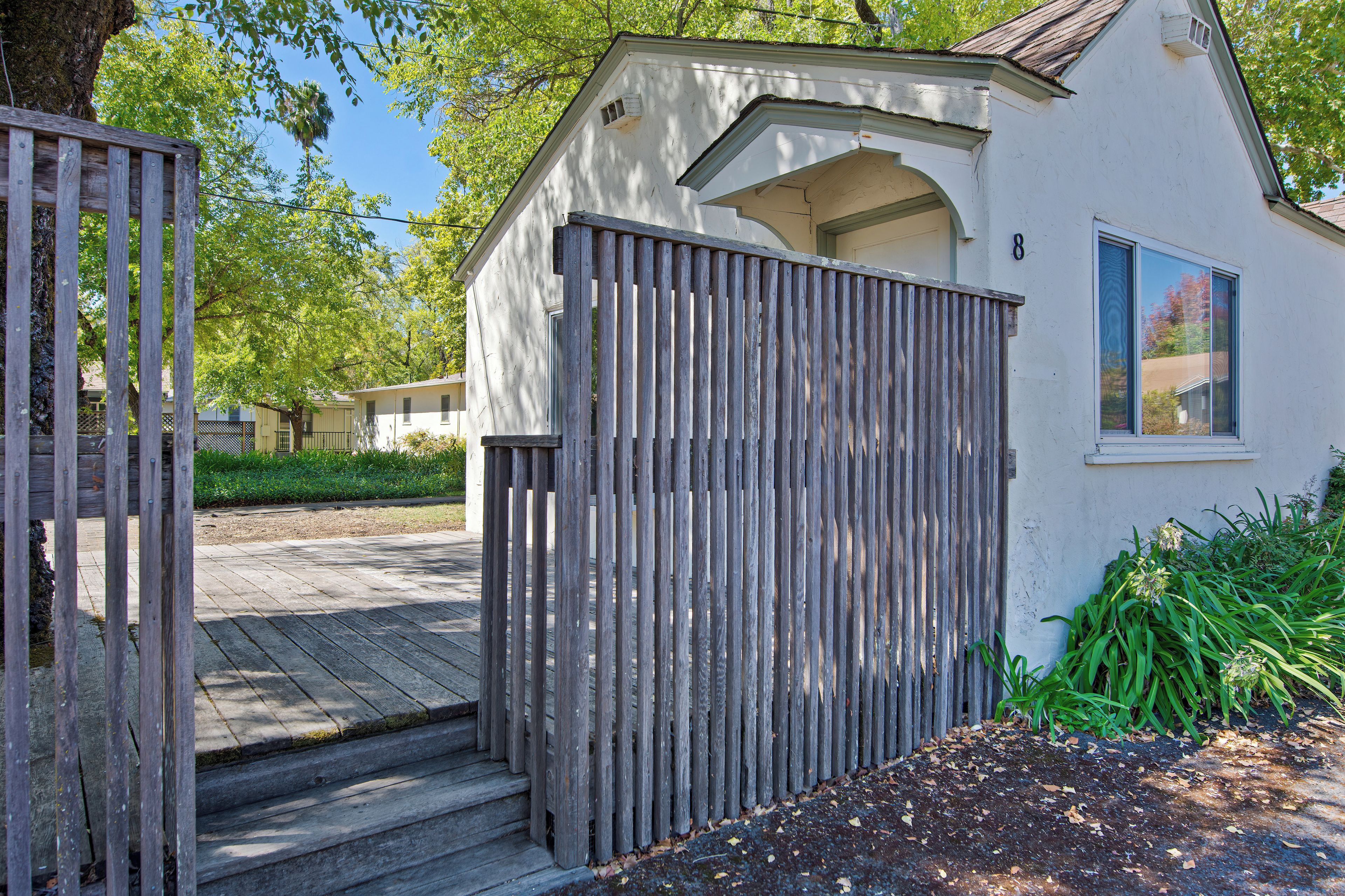 A small, single-story building with a wooden gate and steps leading to a door.