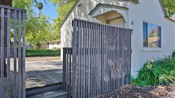 A small, single-story building with a wooden gate and steps leading to a door.