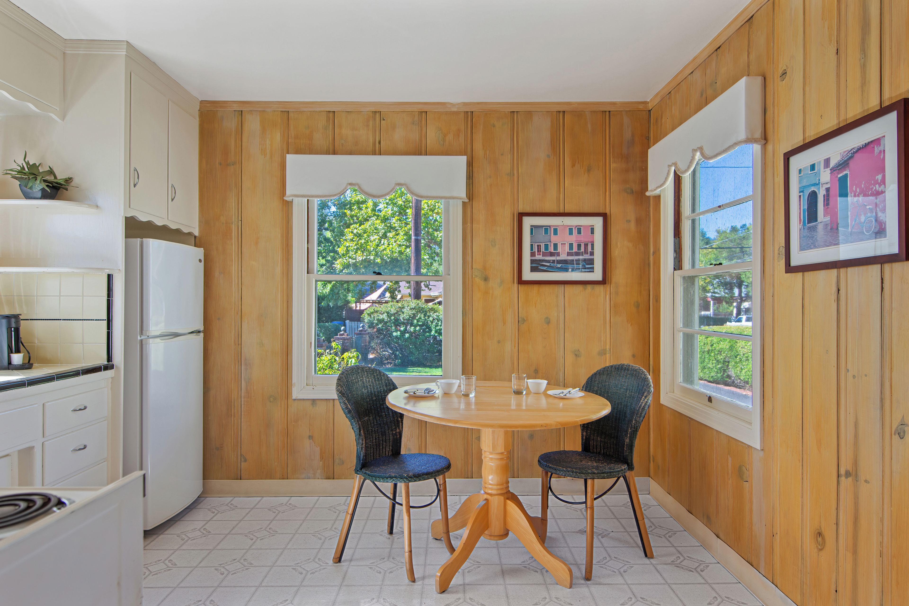 Una cocina compacta con paneles de madera, una mesa de comedor con sillas y vistas por las ventanas.