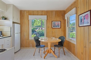 Una cocina compacta con paneles de madera, una mesa de comedor con sillas y vistas por las ventanas.