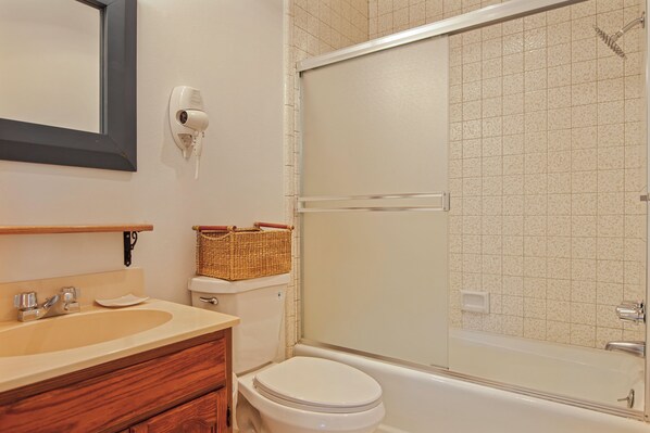 A bathroom with a toilet, sink, and a shower area.