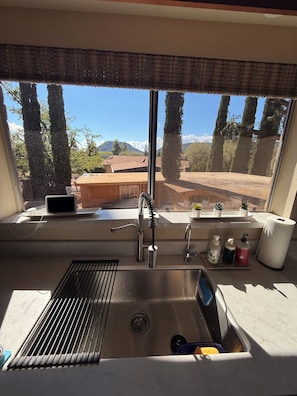 A kitchen with a window view, stainless steel sink, and a small countertop with toiletries. - New renovated 3 bed 3 bath with Castle Rock view, outdoor fire pit -New in vrbo (Sedona)