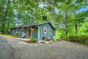 A single-story cabin with a front porch, a satellite dish, and a gravel driveway. - Sunrise Surprise - Guest Favorite (Lake Lure)