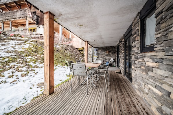 Una terraza de madera con un muro de piedra y un balcón.