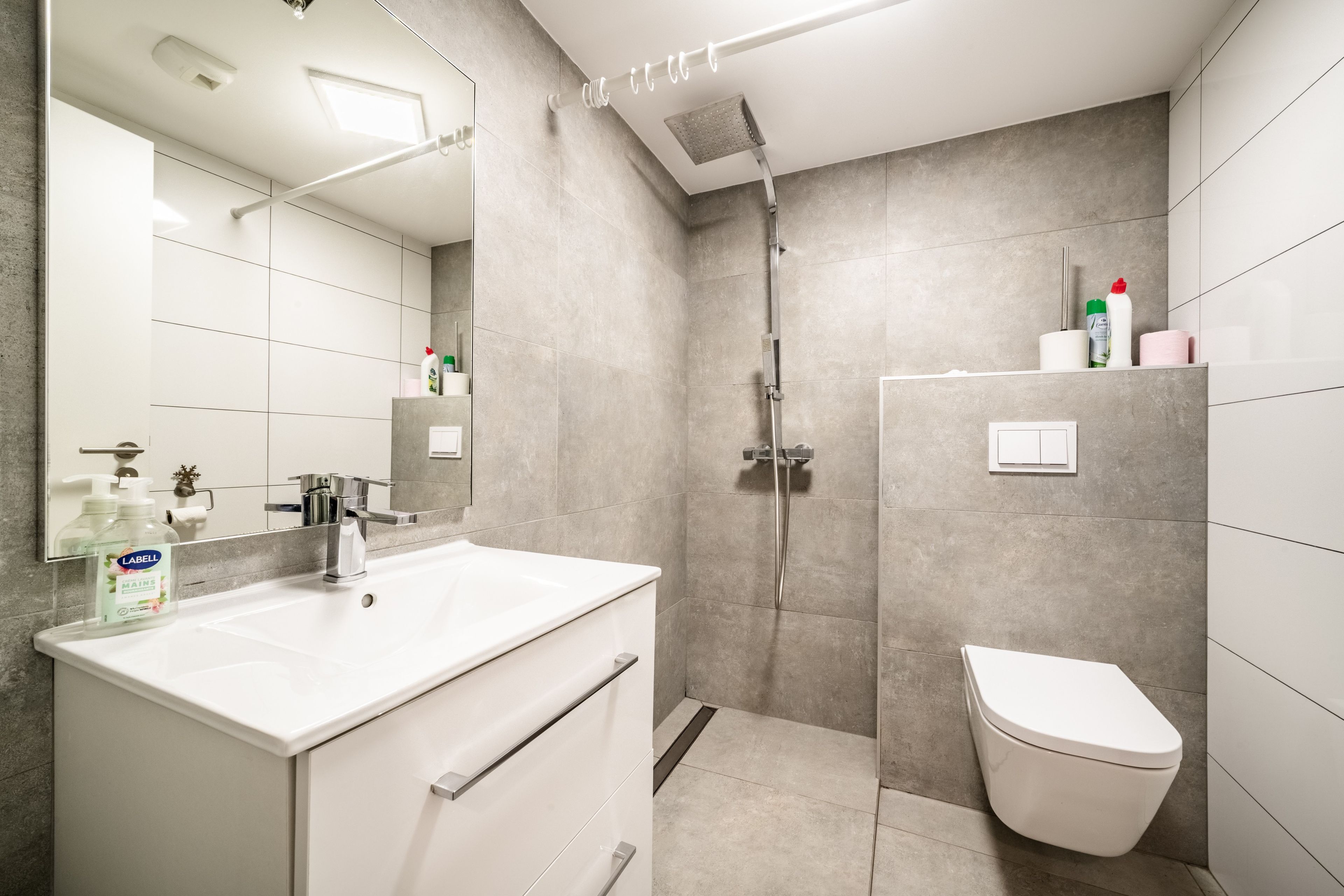 Een moderne badkamer met douche, toilet en wastafel.