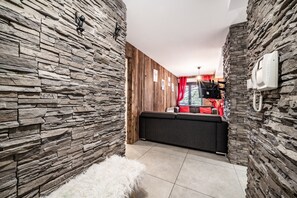 Un interior modern amb parets de pedra, un sofà i una catifes blanca i esponjosa.