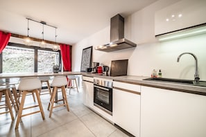 Una cocina moderna con una campana de acero inoxidable, horno integrado y un amplio ventanal con vista a zonas verdes.