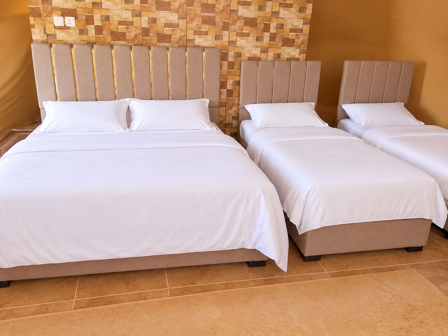 A hotel room with two beds, each with a headboard and white bedding.