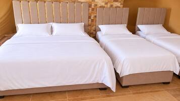 A hotel room with two beds, each with a headboard and white bedding.