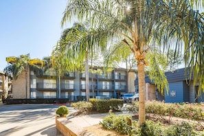 A multi-story building with balconies, a parking area, and landscaped gardens. - Cozy 1-bedroom apartment with AC in Central Houston (Houston)