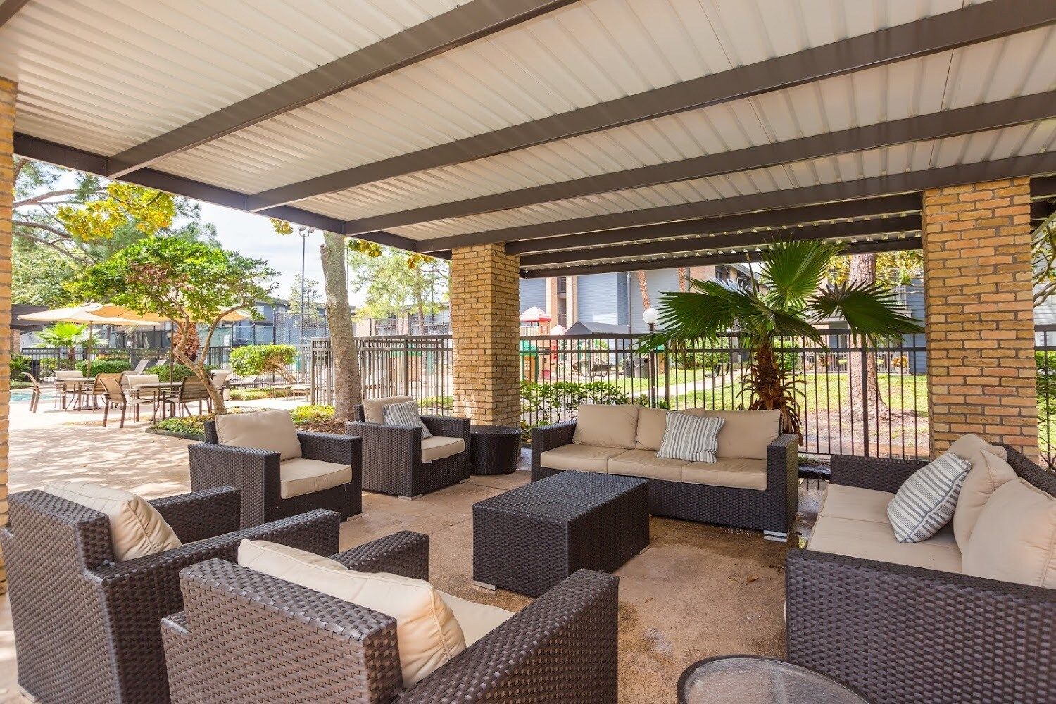 An outdoor patio area with wicker furniture and a brick column.