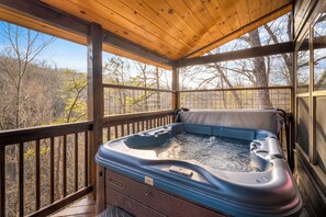 Ein Whirlpool auf einer Holzterrasse mit Blick auf Bäume.