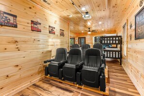 Un interior de madera con una fila de asientos negros estilo teatro, paredes de madera e iluminación empotrada en el techo.