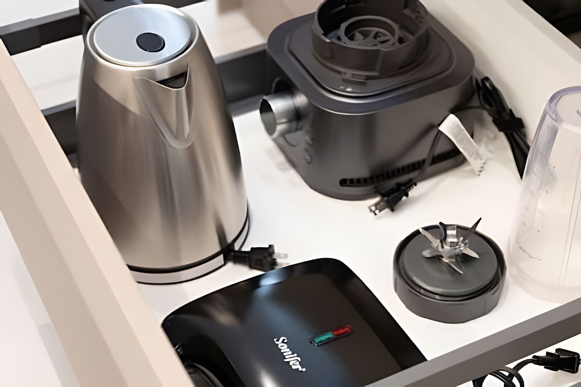 Una encimera de cocina con una cafetera, una licuadora y un recipiente con tapa.