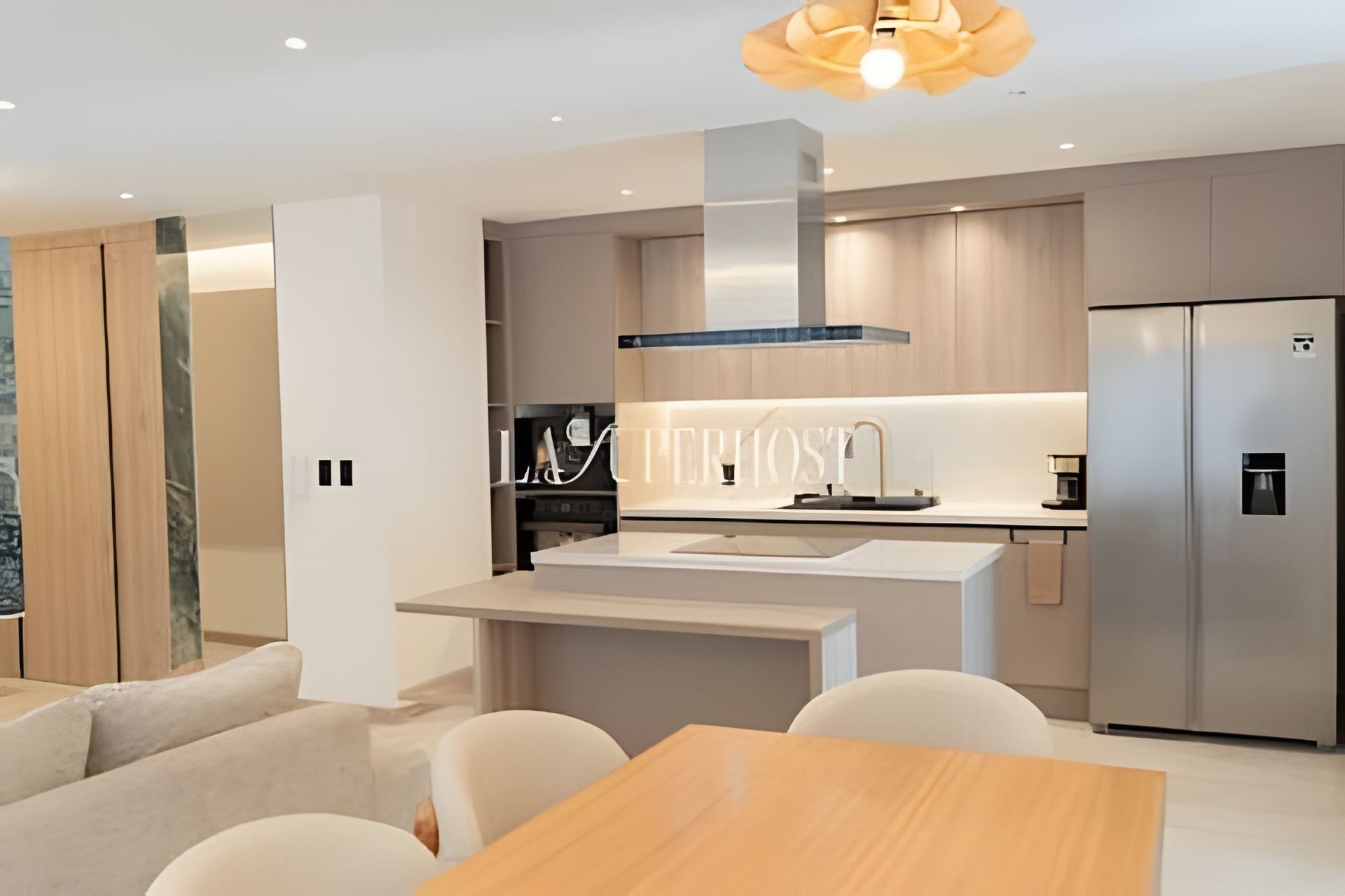 Una cocina moderna con una isla central, electrodomésticos de acero inoxidable y un comedor con mesa y sillas.