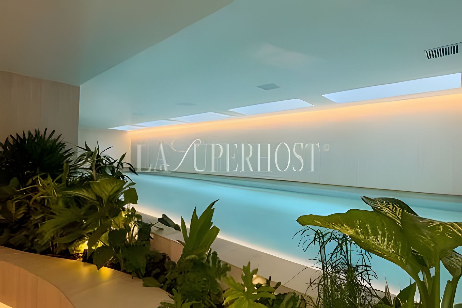 A reception area with a modern design, featuring a reception desk and a wall with the text 'LA SUPERHOST'.