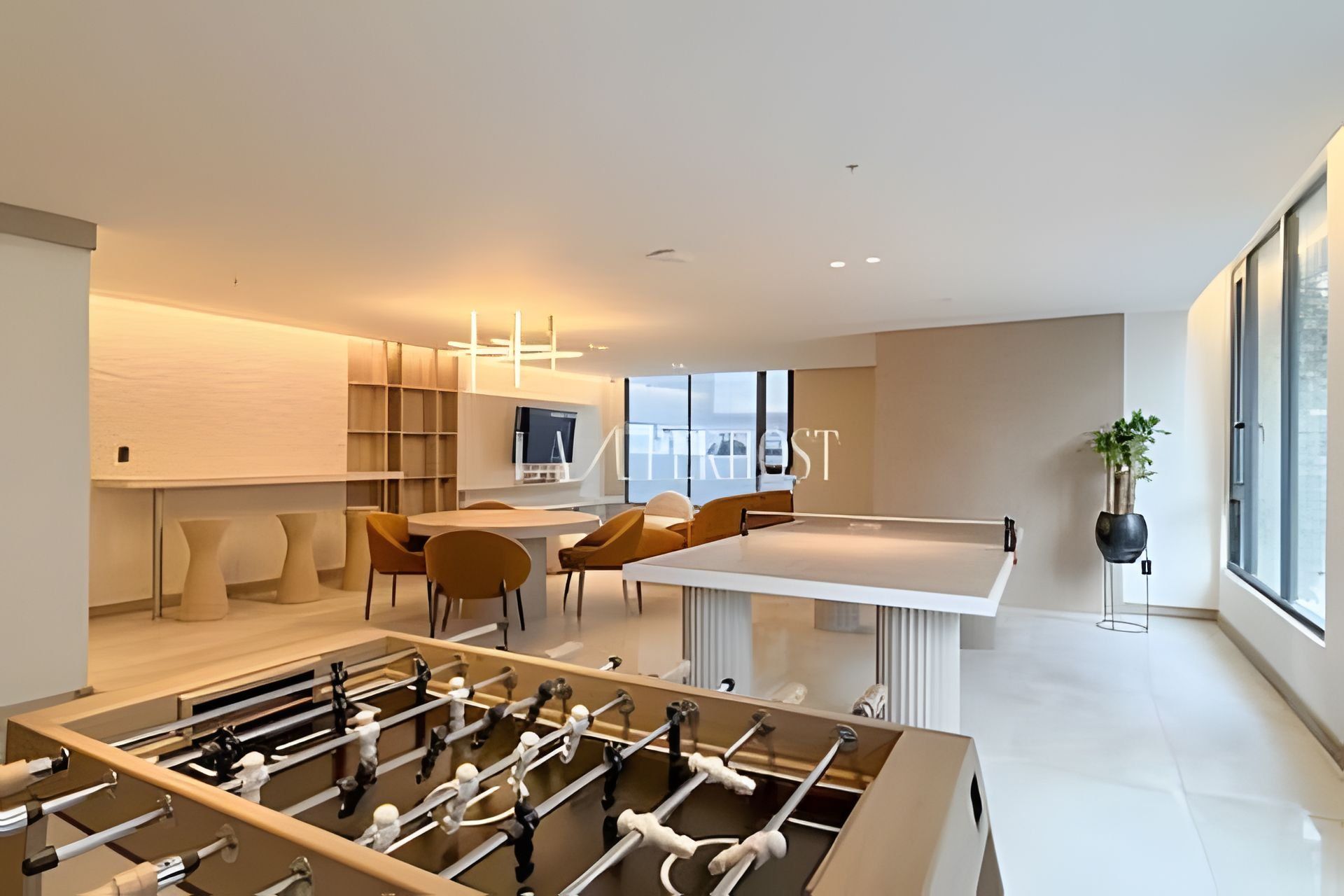 A modern interior with a foosball table, a dining area, and a large window providing natural light.