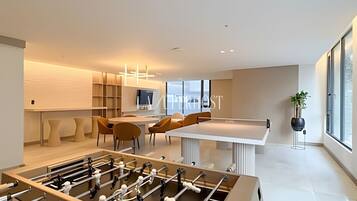 A modern interior with a foosball table, a dining area, and a large window providing natural light.