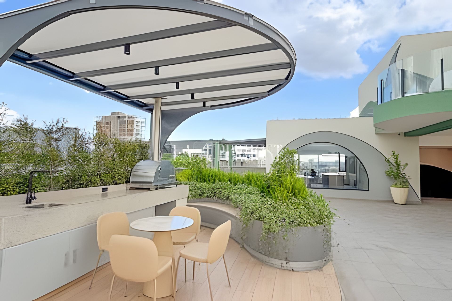 An outdoor patio with a covered seating area, a grill, and a view of the cityscape.