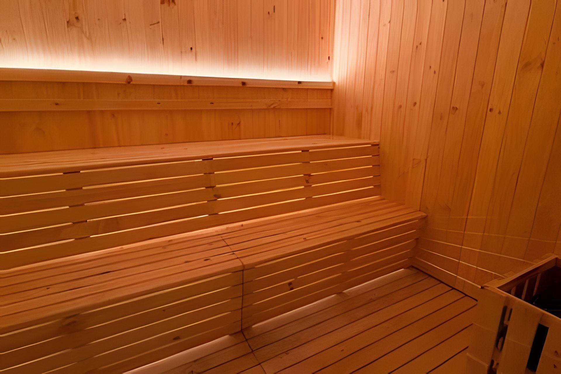 Eine Saunabank aus Holz mit Schlitzmuster, eine Holzwand und ein gefliester Boden.