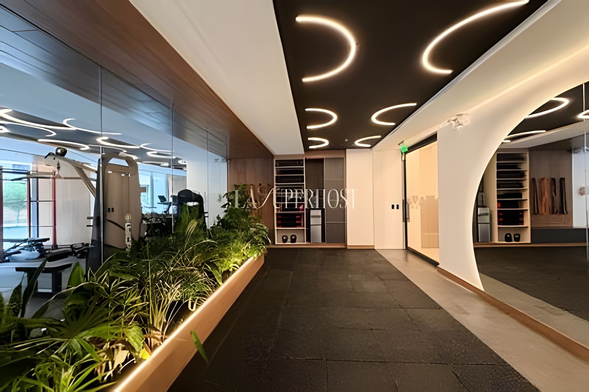 A modern interior with a central corridor, a seating area with a table and chairs, and a plant-lined wall.