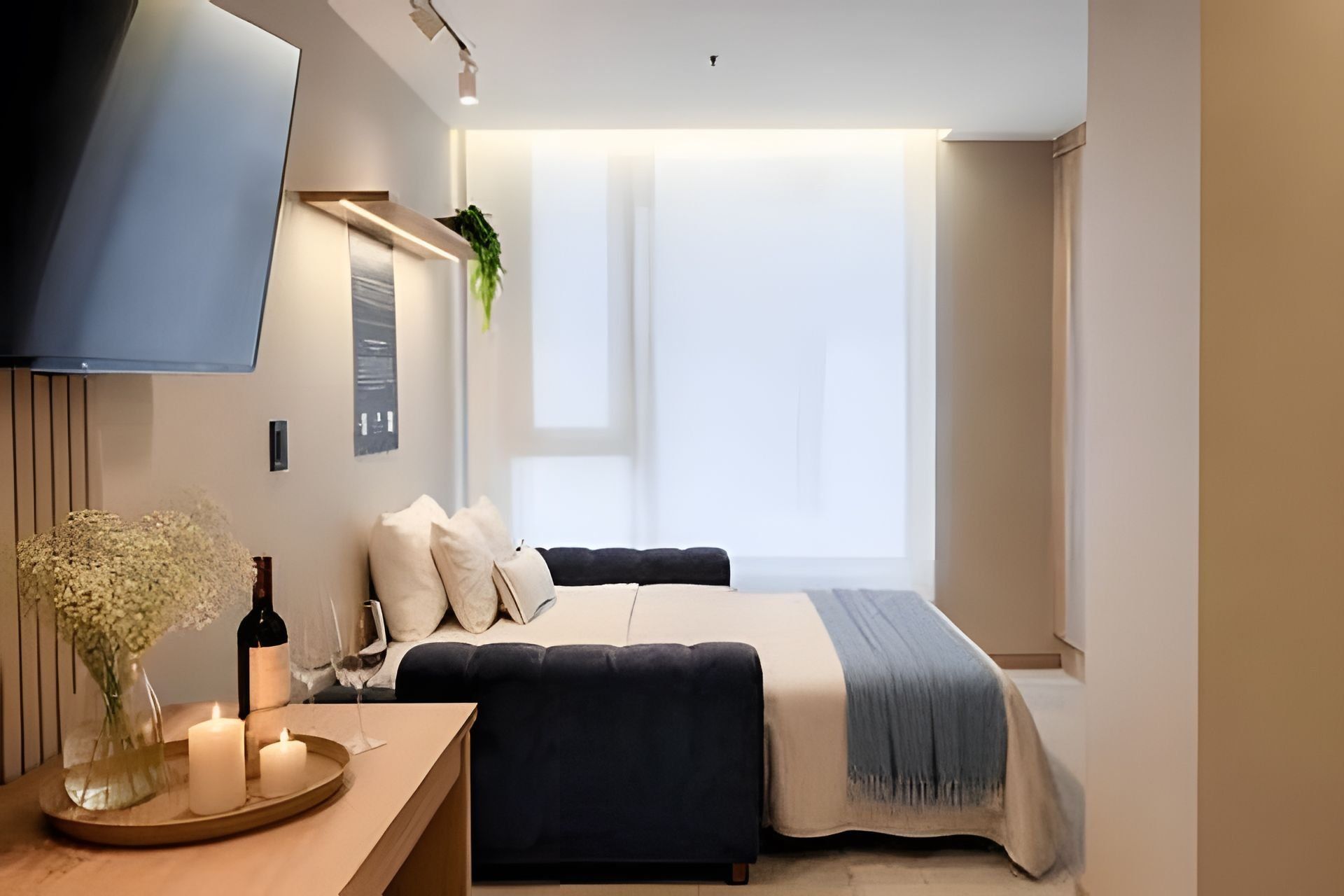 A modern bedroom with a bed, bedside table, and a TV mounted on the wall.