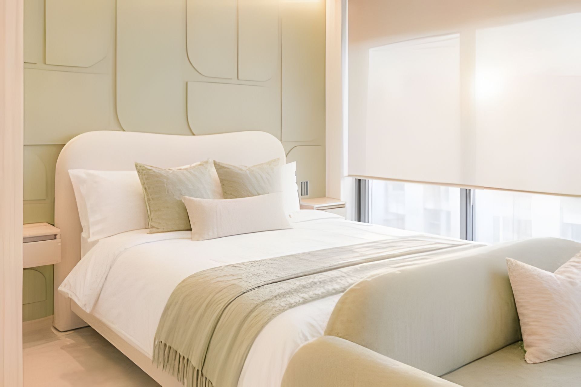 A modern bedroom with a large bed, a nightstand, and a window with curtains.