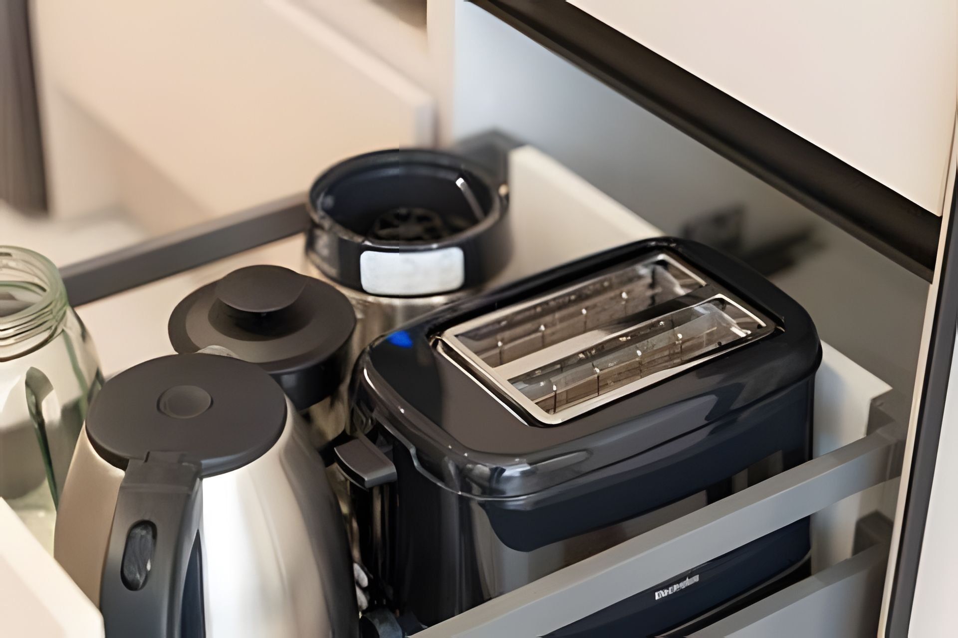 Un cassetto della cucina con un tostapane, un vasetto e un contenitore.
