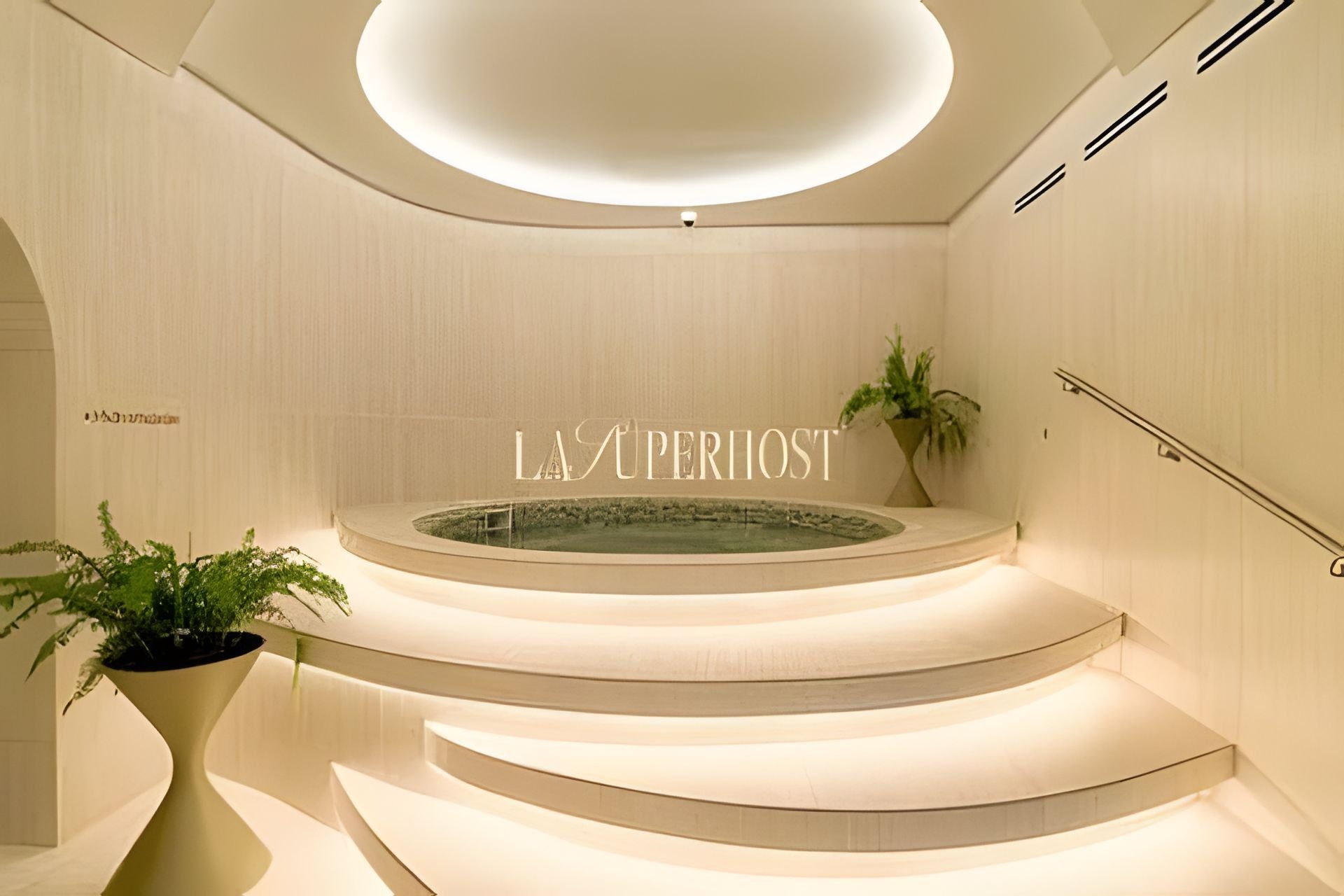 Un interior moderno con una escalera curva, una fuente central y un letrero que dice 'LA SUPERIOST'.