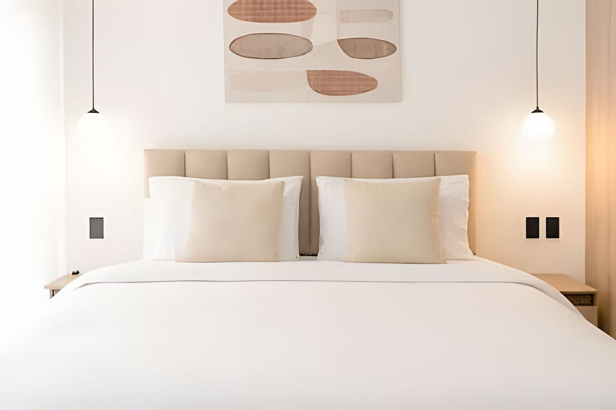 Un dormitorio moderno con una cama grande, dos mesitas de noche e iluminación colgante.
