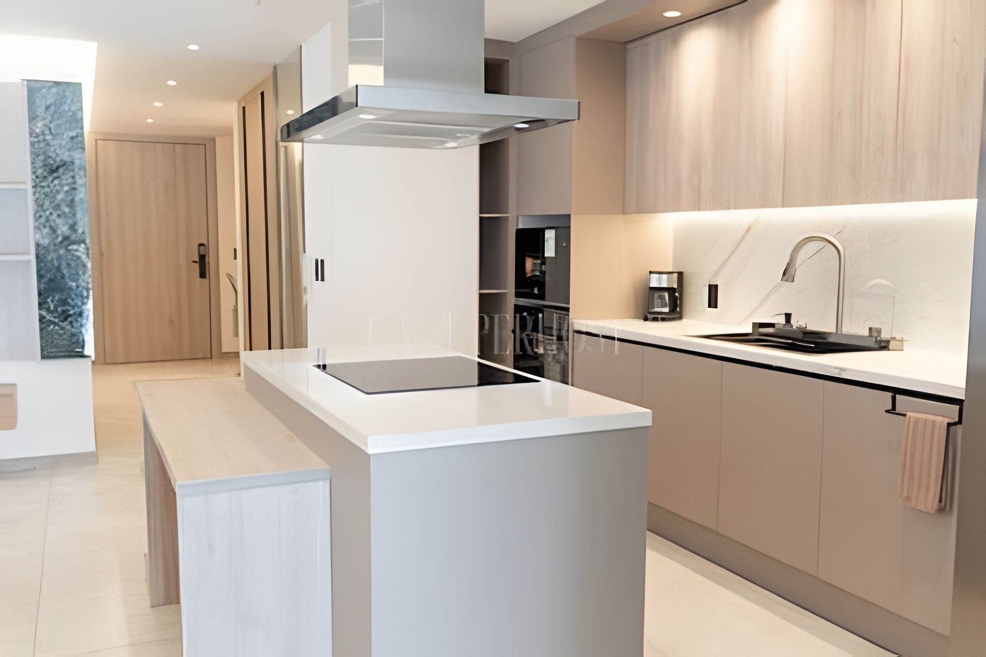 Een moderne keuken met een centraal eiland, inbouwmeubels en een roestvrijstalen afzuigkap.