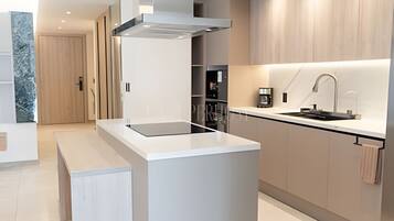 Een moderne keuken met een centraal eiland, inbouwmeubels en een roestvrijstalen afzuigkap.