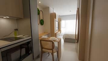 A hotel room with a kitchenette, a dining area with a chair, a bed, and a large window.