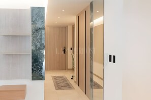 Un interior modern amb una porta de fusta, un mur amb un disseny i una paret d'accent de marbre.