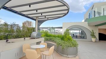 Een terras buiten met een overdekte zithoek, een barbecue en uitzicht op de stad.