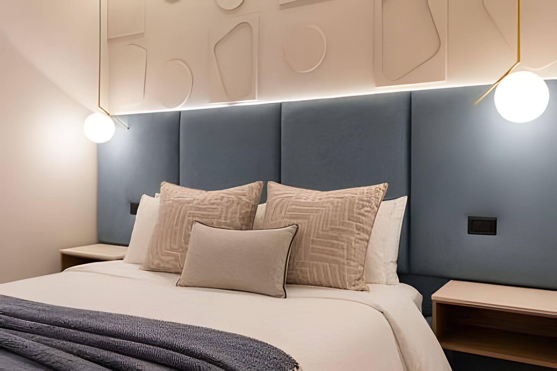 Une chambre à coucher moderne, avec un lit, des tables de chevet et une tête de lit ornée de motifs géométriques.