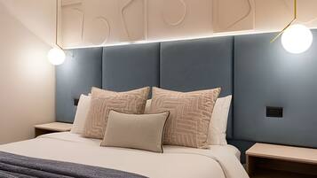 Une chambre à coucher moderne, avec un lit, des tables de chevet et une tête de lit ornée de motifs géométriques.