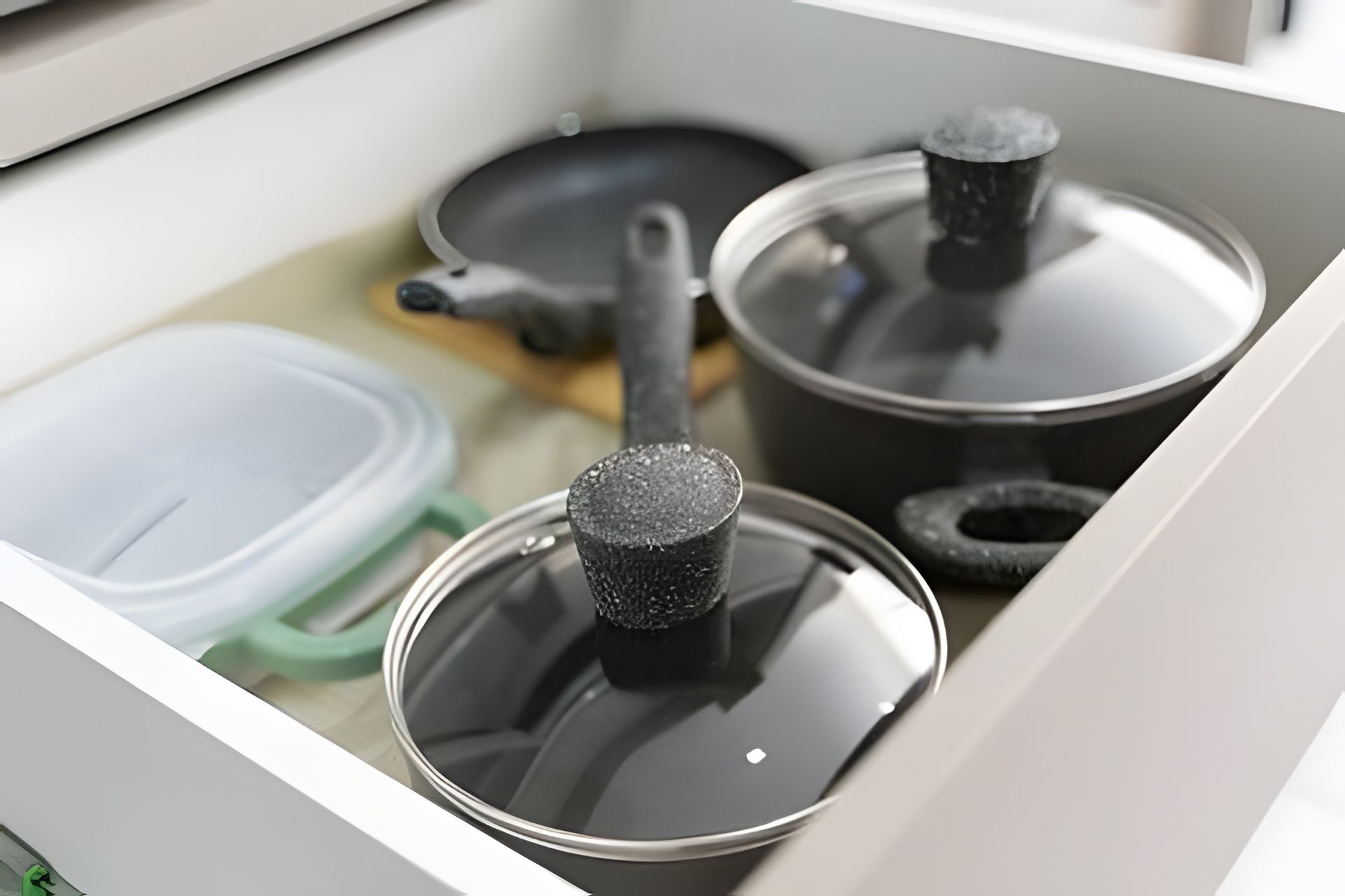 Un cajón de cocina con ollas y sartenes.