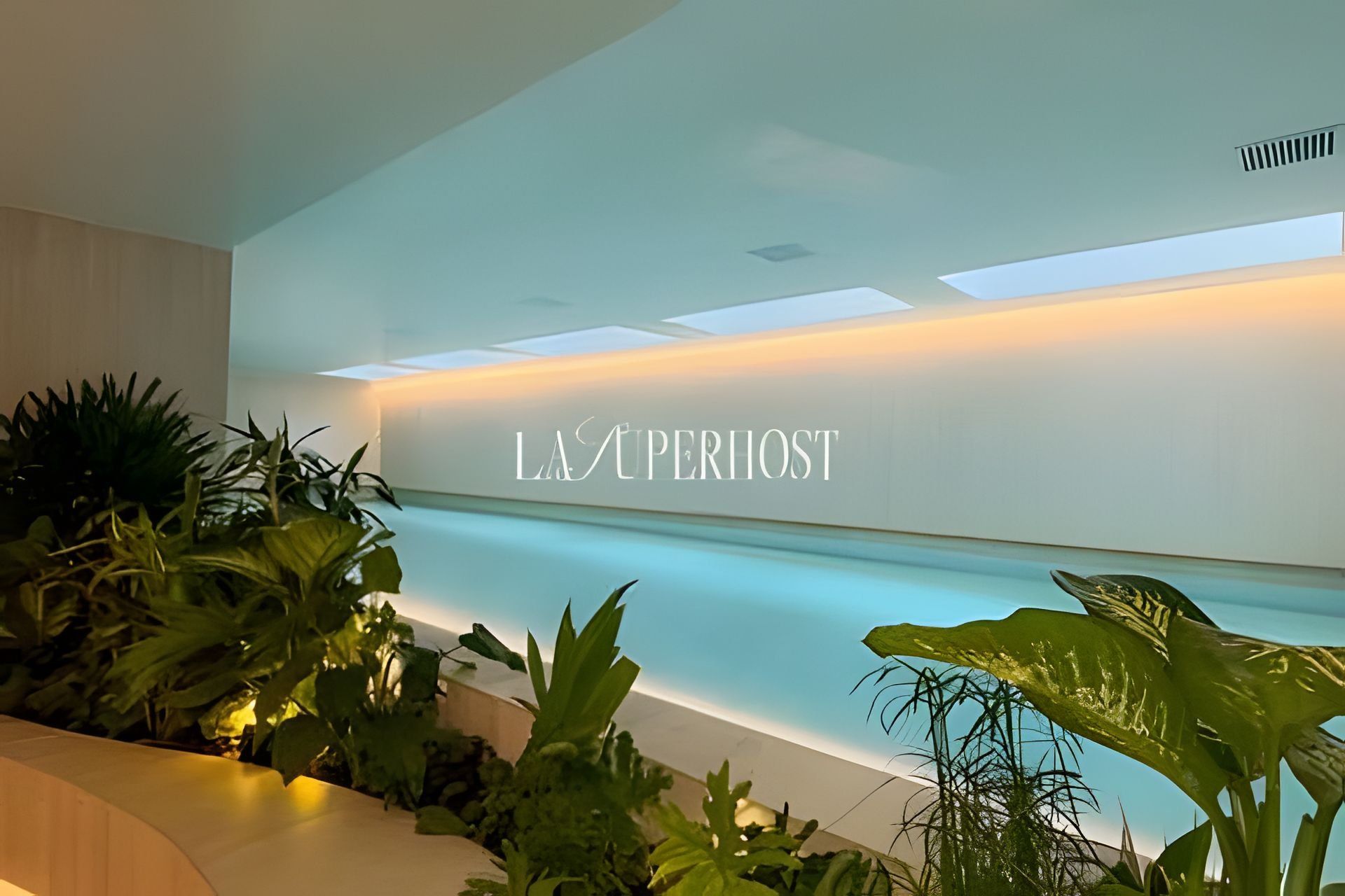 Un área de recepción de diseño moderno, con mostrador de recepción y una pared que muestra el texto 'LAS PERIHOST'.