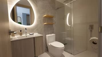 A modern bathroom with a toilet, sink, and glass shower enclosure.