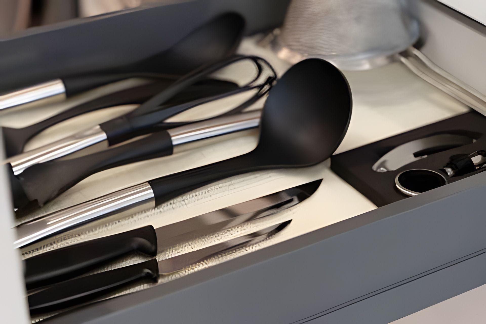 Eine Schublade mit Küchenutensilien, darunter Messer, ein Löffel und ein Pfannenwender.