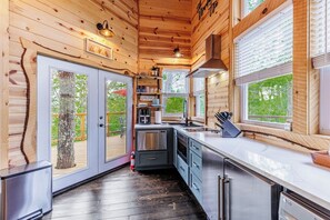 Eine moderne Küche mit Holzwänden, einer Edelstahl-Spüle und einem eingebauten Backofen.
