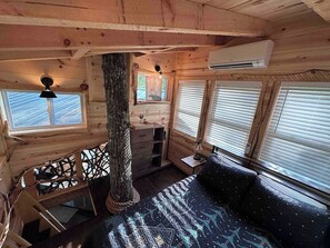 A cabin interior with a bed, a desk, and a window. - Treehouse Escape w/Hot Tub, Near Smoky Mtn (Bryson City)