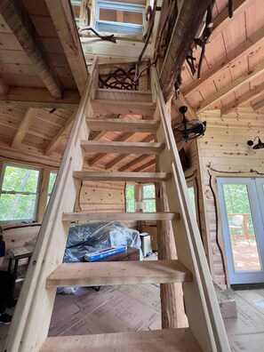 A wooden staircase in a cabin with a sloped ceiling and large windows. - Treehouse Escape w/Hot Tub, Near Smoky Mtn (Bryson City)