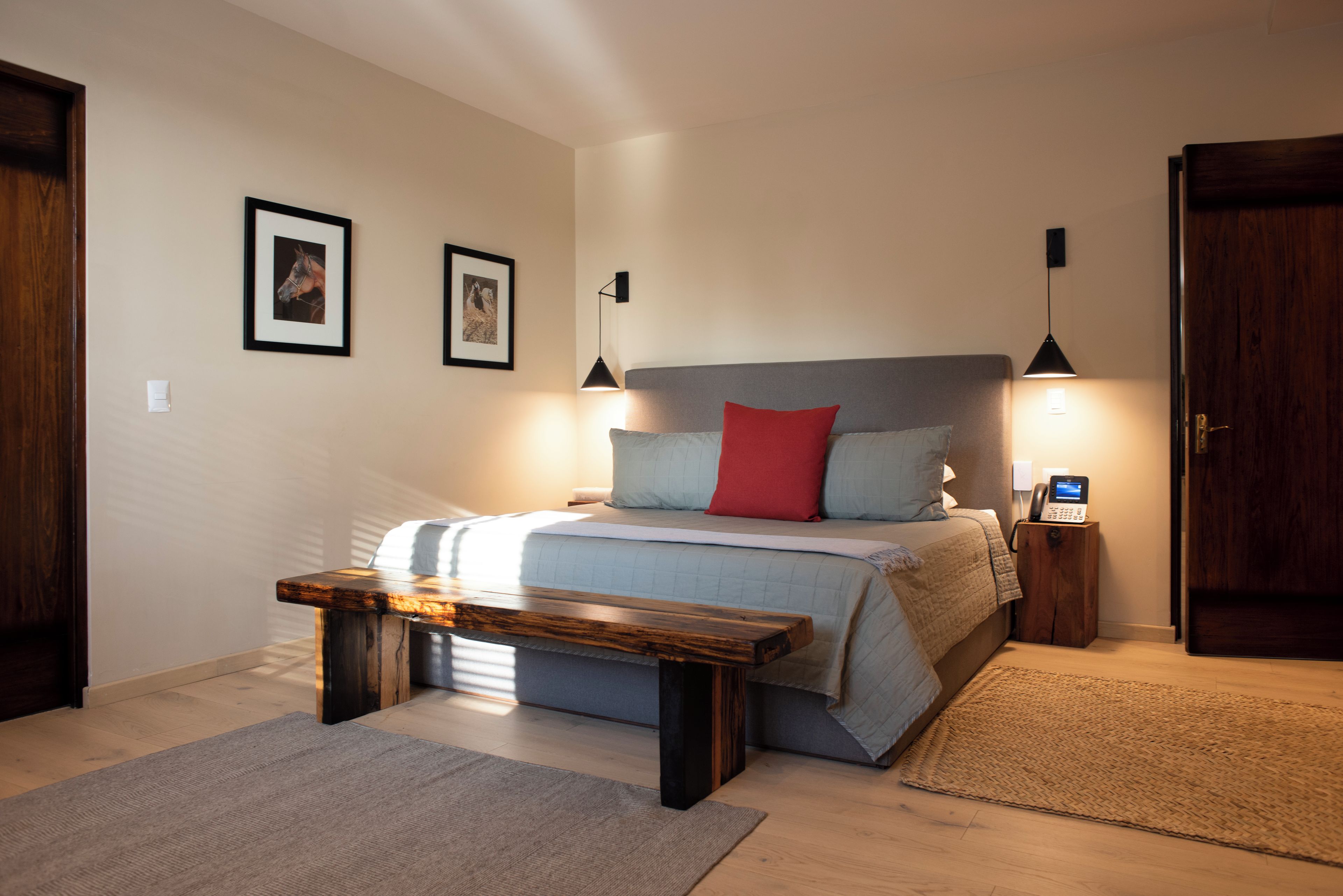 Ein Schlafzimmer mit einem Bett, Nachttischlampen, einem Telefon am Nachttisch und einer Bank.