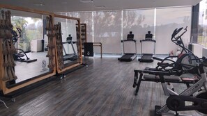 A gym with exercise equipment, a treadmill, and a mirror.