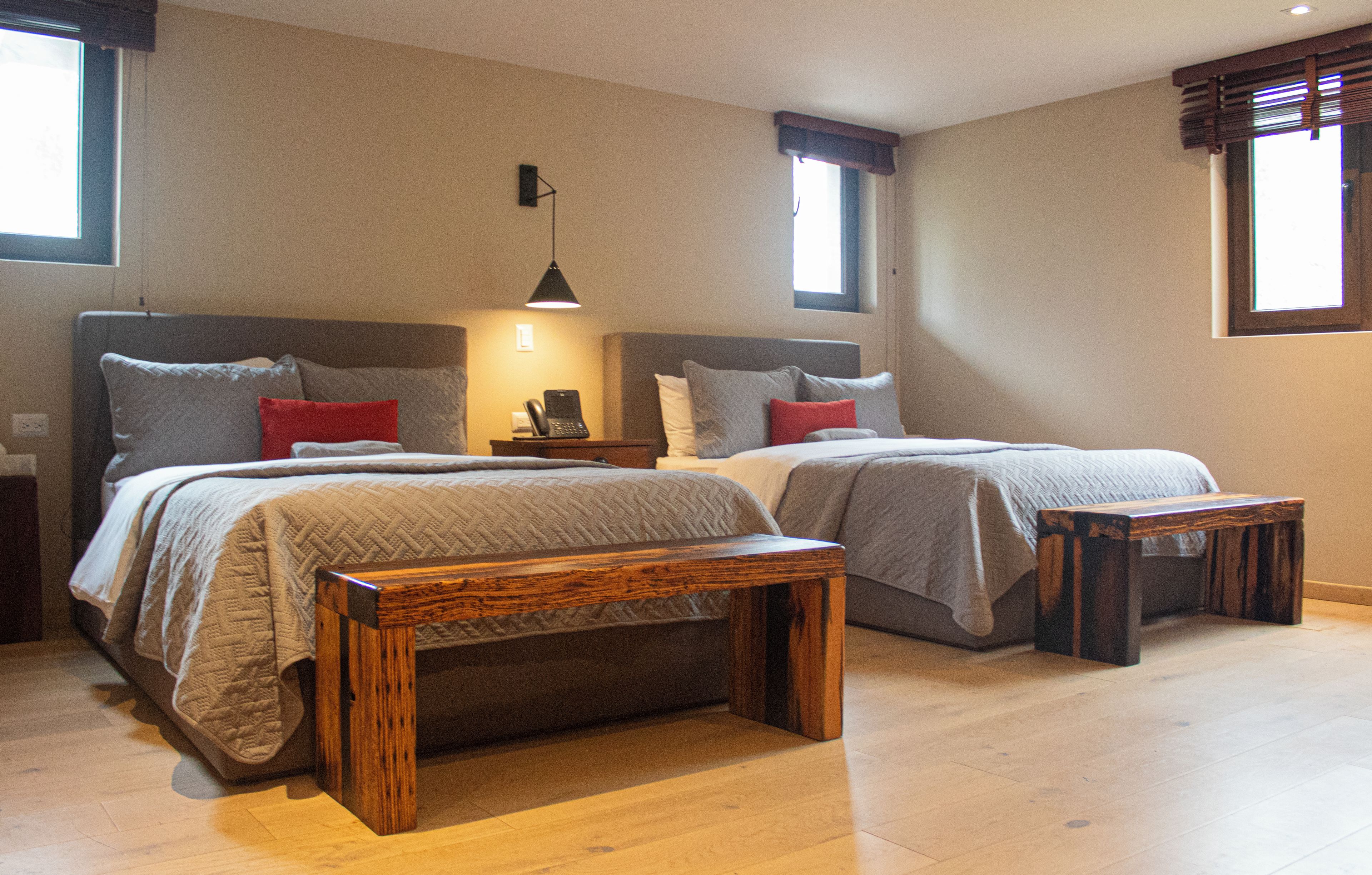 A double room with two beds, a bedside table, a lamp, and a window.