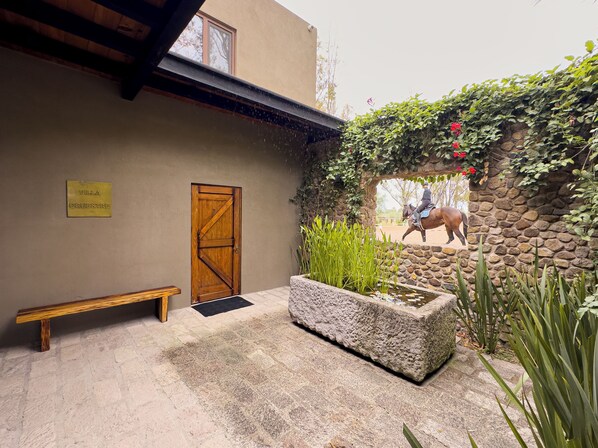 A stone wall with a horse, a wooden door, and a bench.